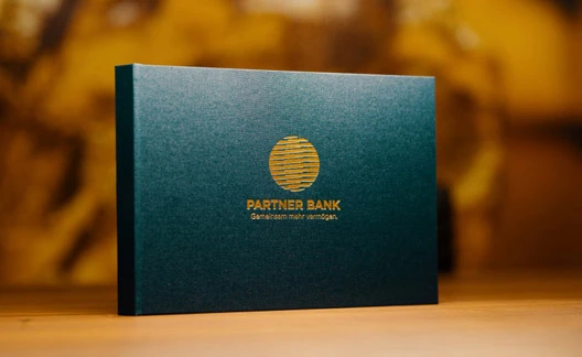 Ein Fokusbuch mit goldener Aufschrift „PARTNER BANK“, das Anlagemöglichkeiten anbietet.