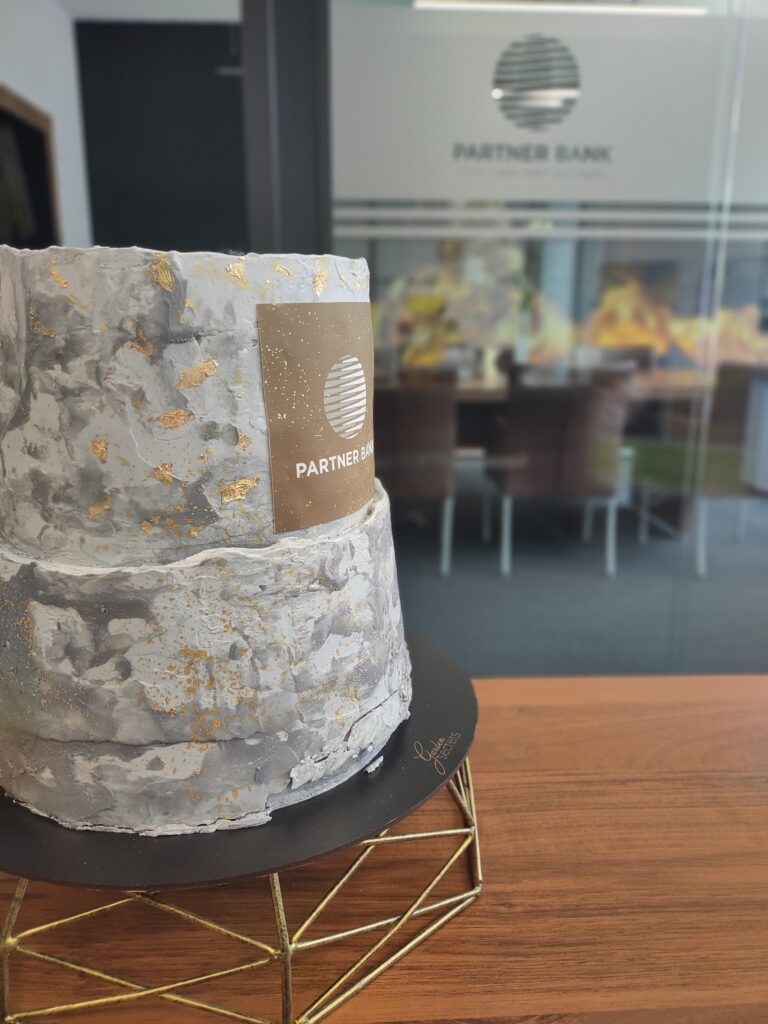 Eine festliche Torte mit Partner Bank-Logo feiert die Büroeröffnung in Brünn, Tschechien. 