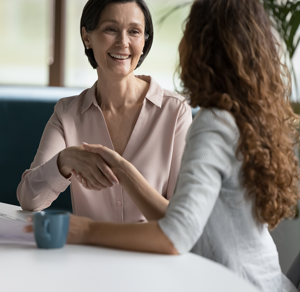 Finanzberaterin schüttelt einer Kundin die Hand während einer persönlichen Finanzberatung in einem modernen Büro