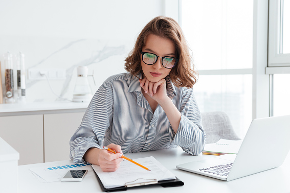 Woman reviewing financial documents and planning next steps toward financial freedom with laptop and calculator at desk