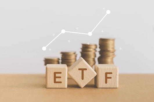ETF-Sparplan mit ETF-Holzwürfeln, Münzstapeln und Wachstumskurve